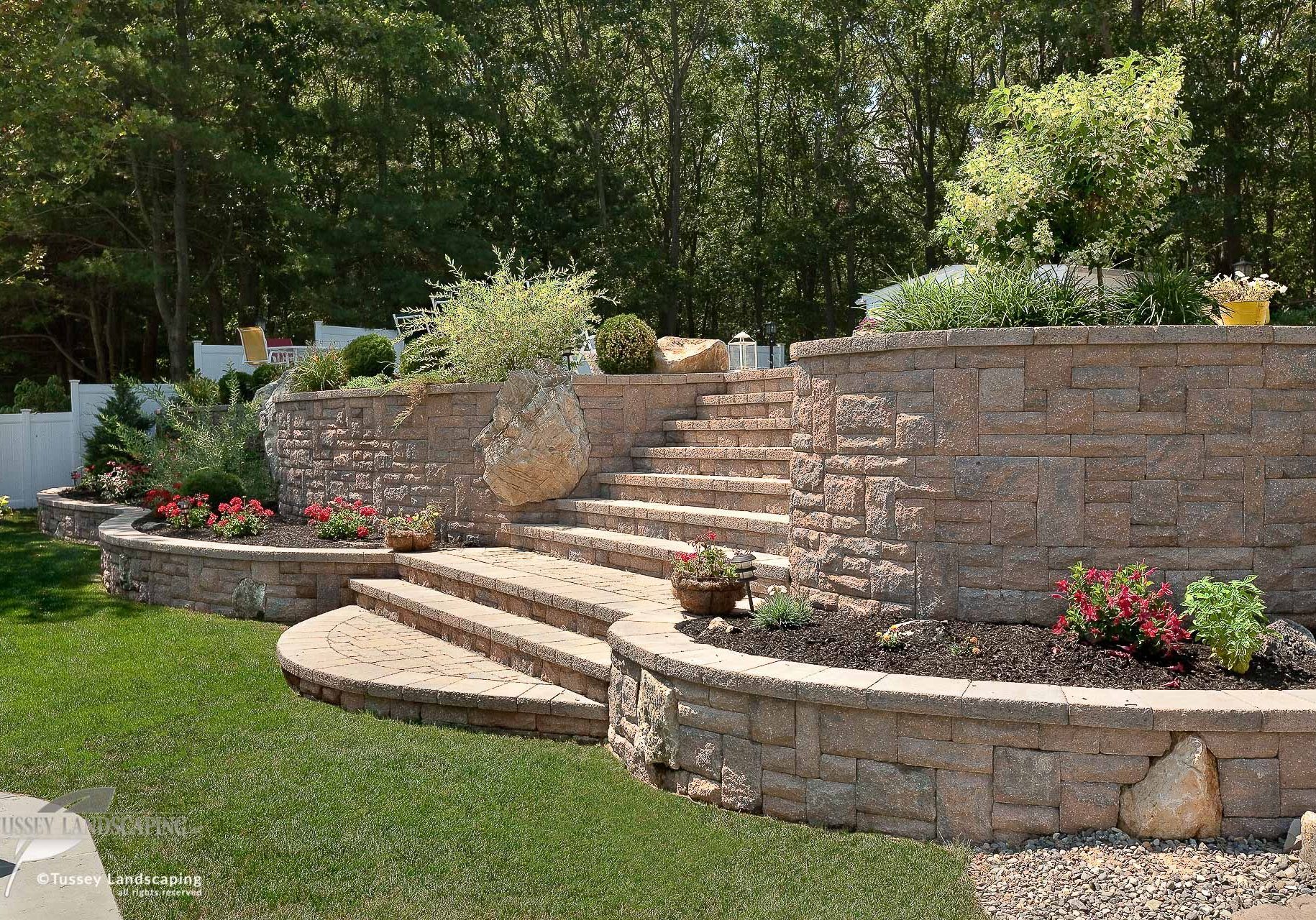 A stone retaining wall in a backyard.